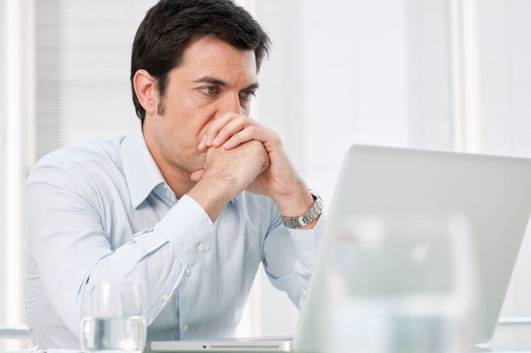 Worried man at computer trying to find the right criminal defence lawyer after being charged with a crime and facing the prospect of going to prison.